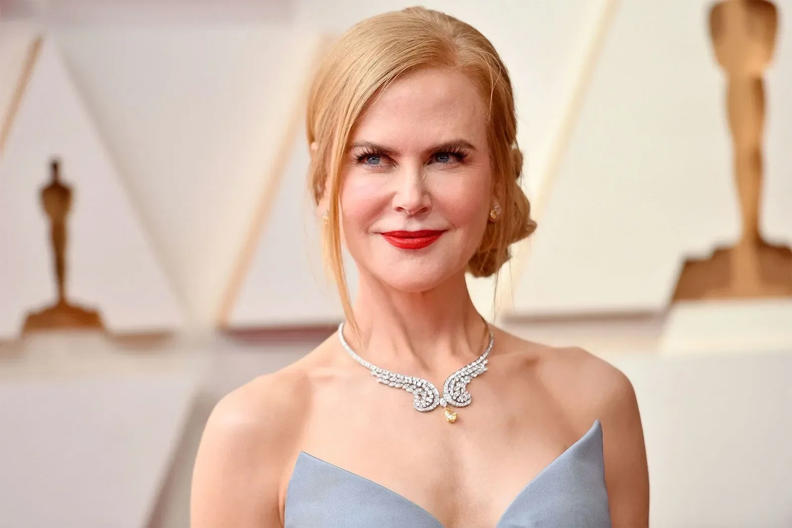 Nicole Kidman tersenyum di karpet merah, mengenakan gaun biru muda dan kalung berlian.