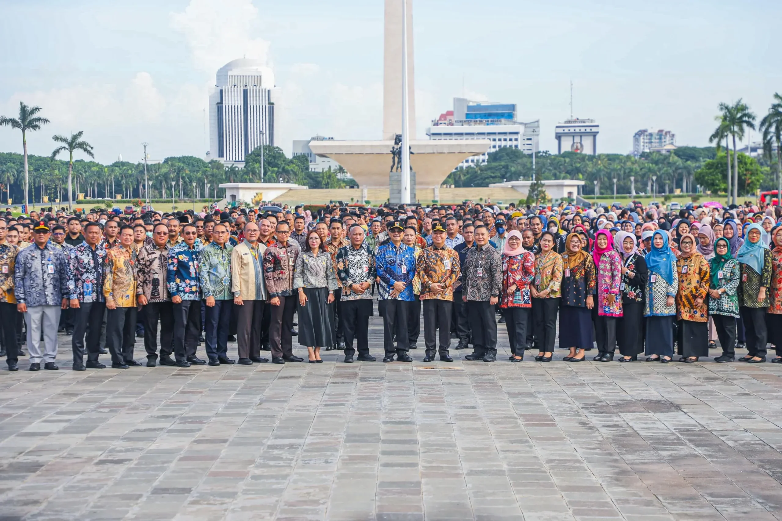 Sekelompok besar orang berbaris di depan Monumen Nasional, Jakarta.