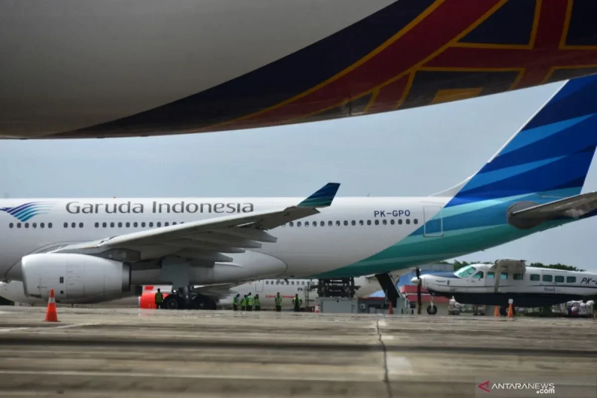 Pemandangan pesawat Garuda Indonesia dan pesawat lain di apron bandara.