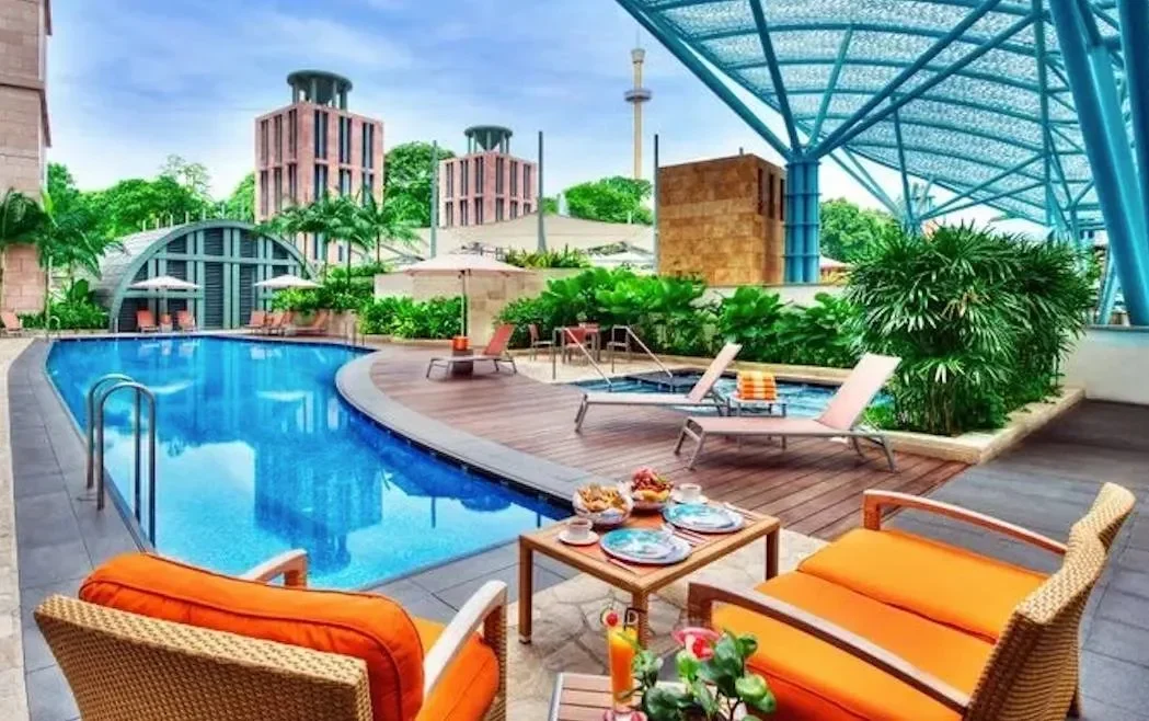 Kolam renang mewah di Singapura dengan kursi santai dan pemandangan gedung-gedung.