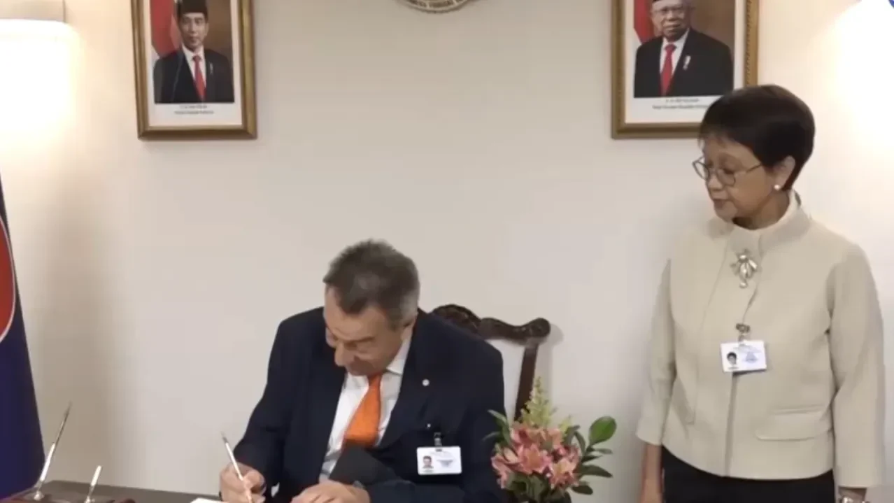 Menlu Retno Marsudi bersama pejabat asing di ruang pertemuan dengan potret presiden RI