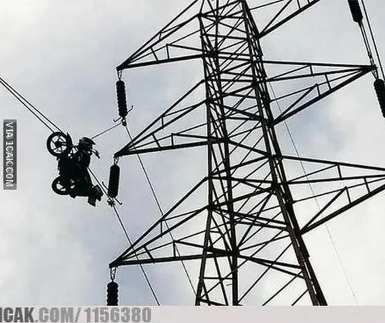Sepeda motor tergantung di kabel listrik menara tegangan tinggi, ilustrasi bahaya berkendara.