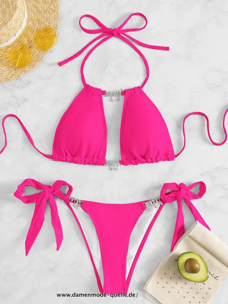 Bikini berwarna pink cerah dengan aksen tali dan hiasan berkilau.