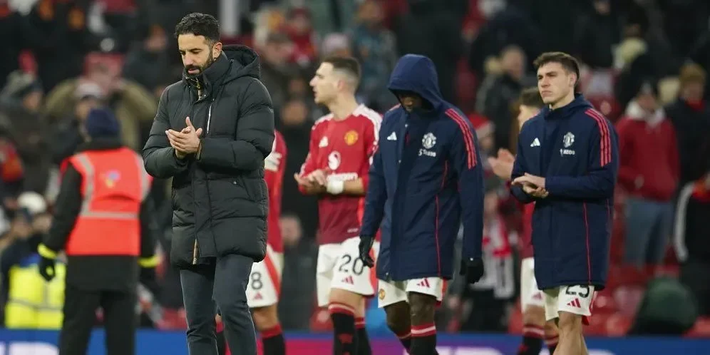 Pelatih dan pemain Manchester United berjalan di lapangan dengan ekspresi prihatin.