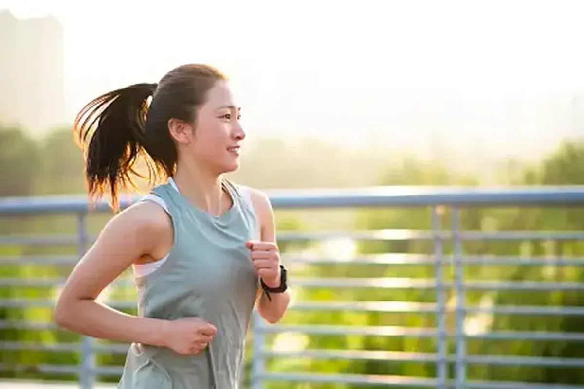 Wanita muda tersenyum saat berolahraga lari di pagi hari menikmati udara segar.
