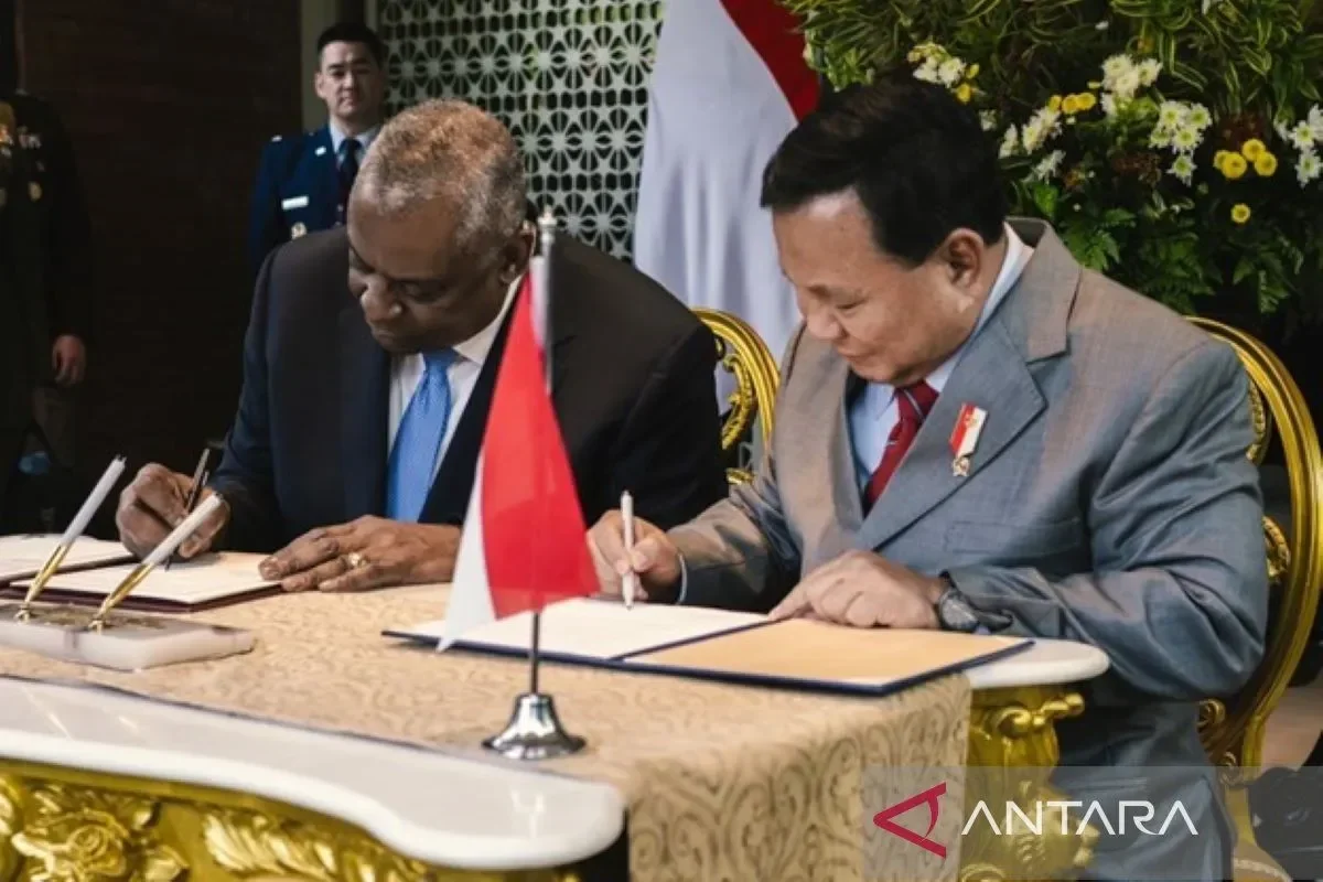 Dua pejabat menandatangani dokumen penting, menandai pakta pertahanan strategis.