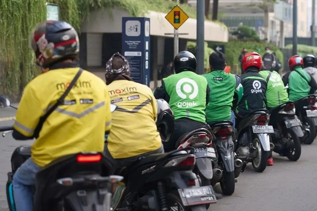 Sekelompok pengemudi ojek online Maxim dan Gojek berbaris di jalan.