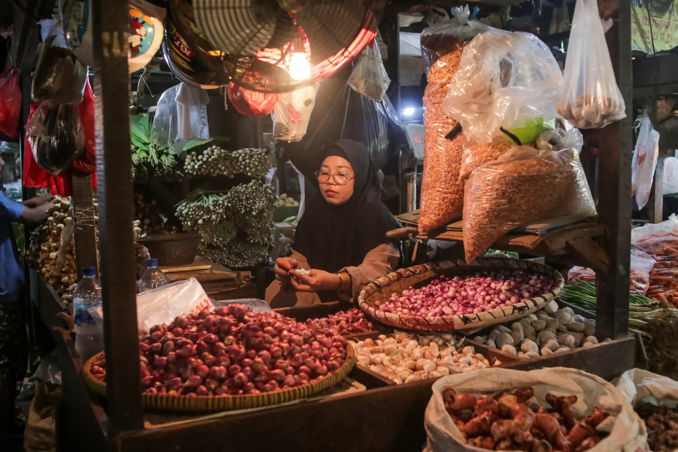 Pedagang di pasar malam menyiapkan bawang merah dan bawang putih untuk dijual.