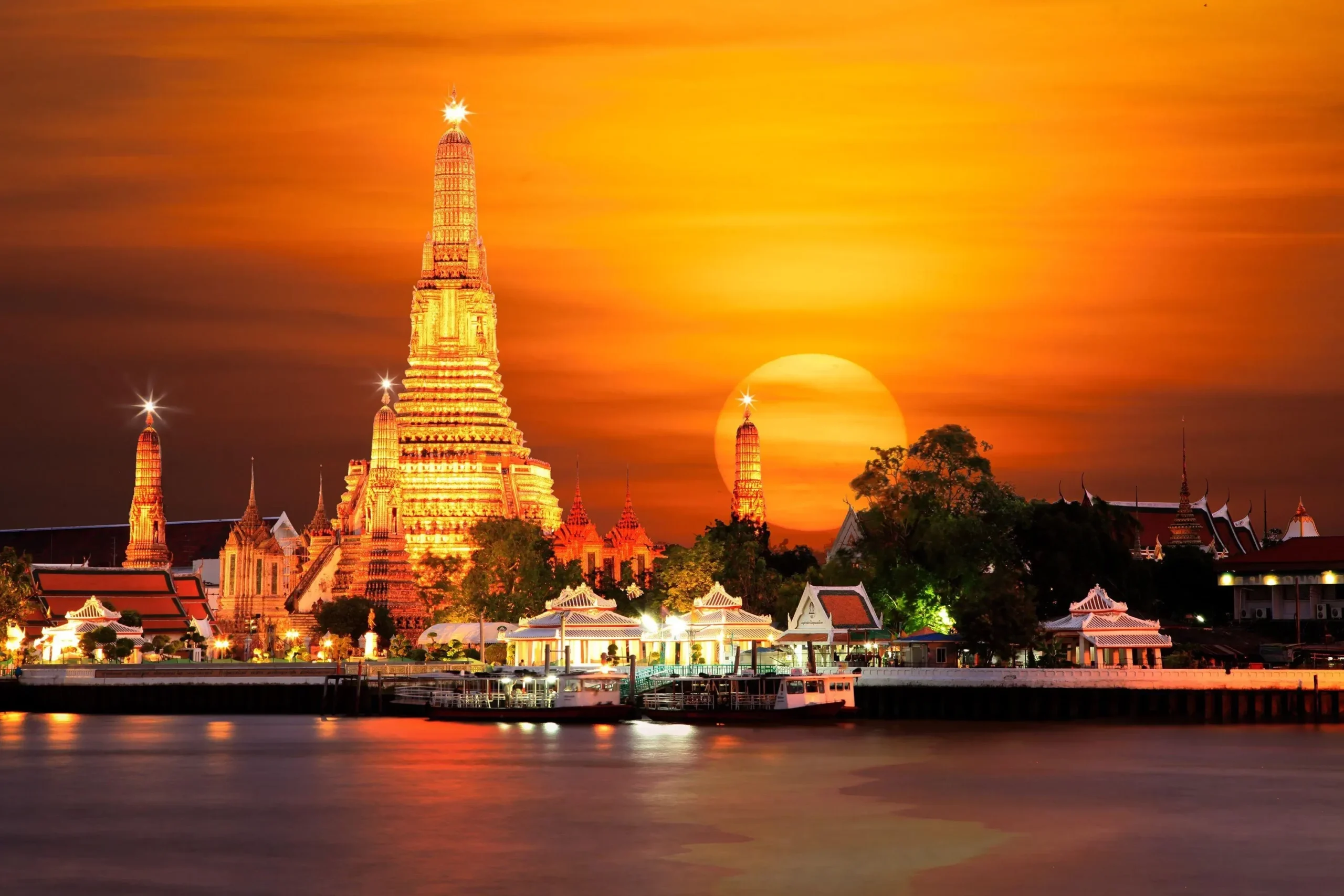 Wat Arun, kuil Buddha di Bangkok, Thailand, diterangi cahaya senja keemasan.