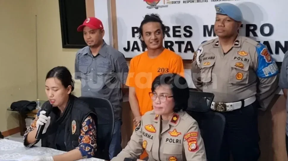 Vadel Badjideh didampingi polisi dan wanita berpakaian dinas di kantor polisi.