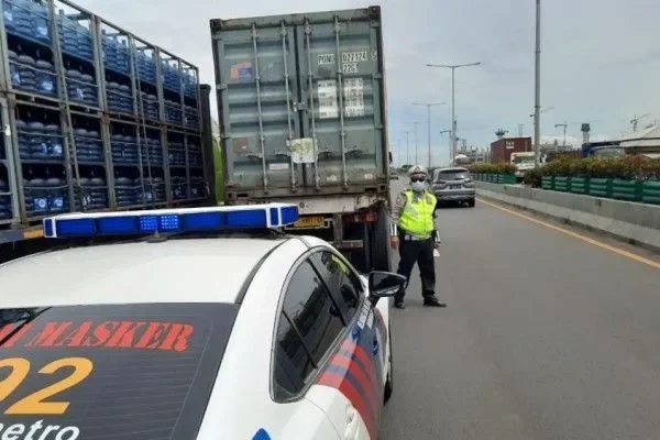 Mobil polisi dengan strobo biru sedang bertugas di jalan raya, lalu lintas padat.