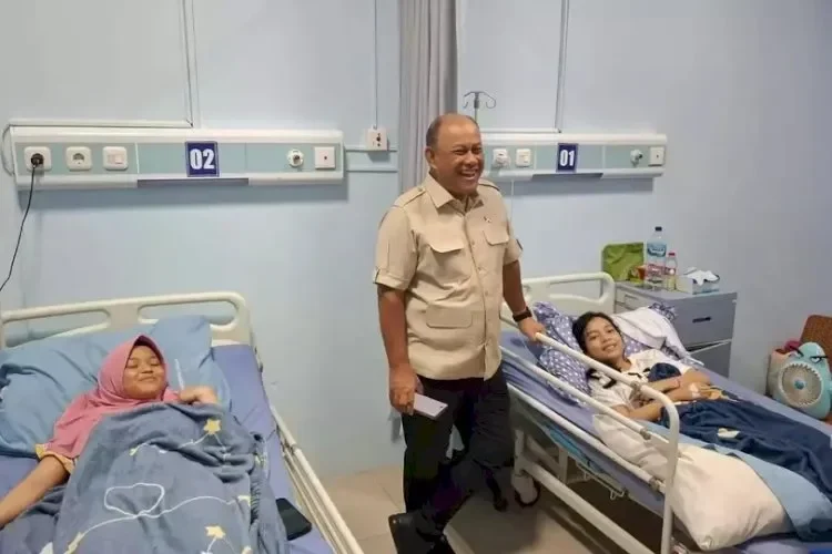 Anak-anak terbaring di ranjang rumah sakit, seorang pria dewasa berdiri di antara mereka.