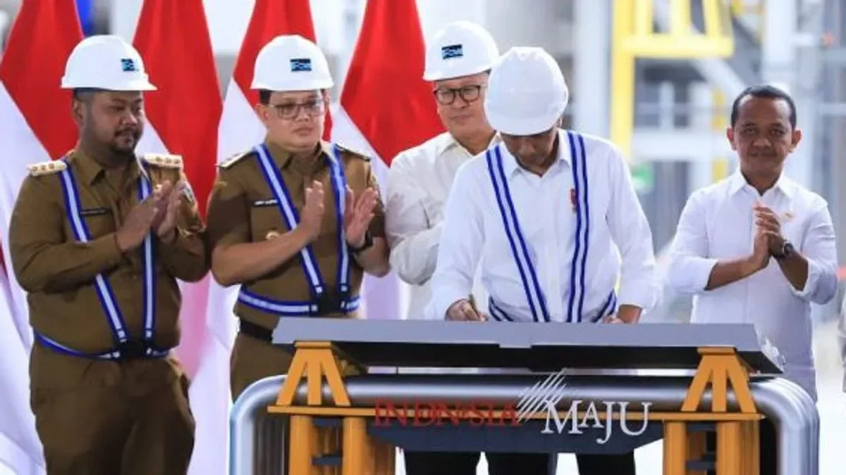 Pejabat pemerintah dan pekerja tambang di depan bendera Indonesia.