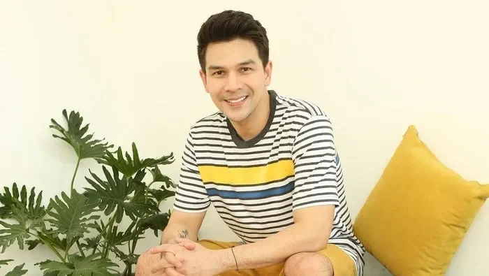 Jonathan Frizzy alias Ijonk tersenyum. Memakai kaus bergaris dan celana pendek.