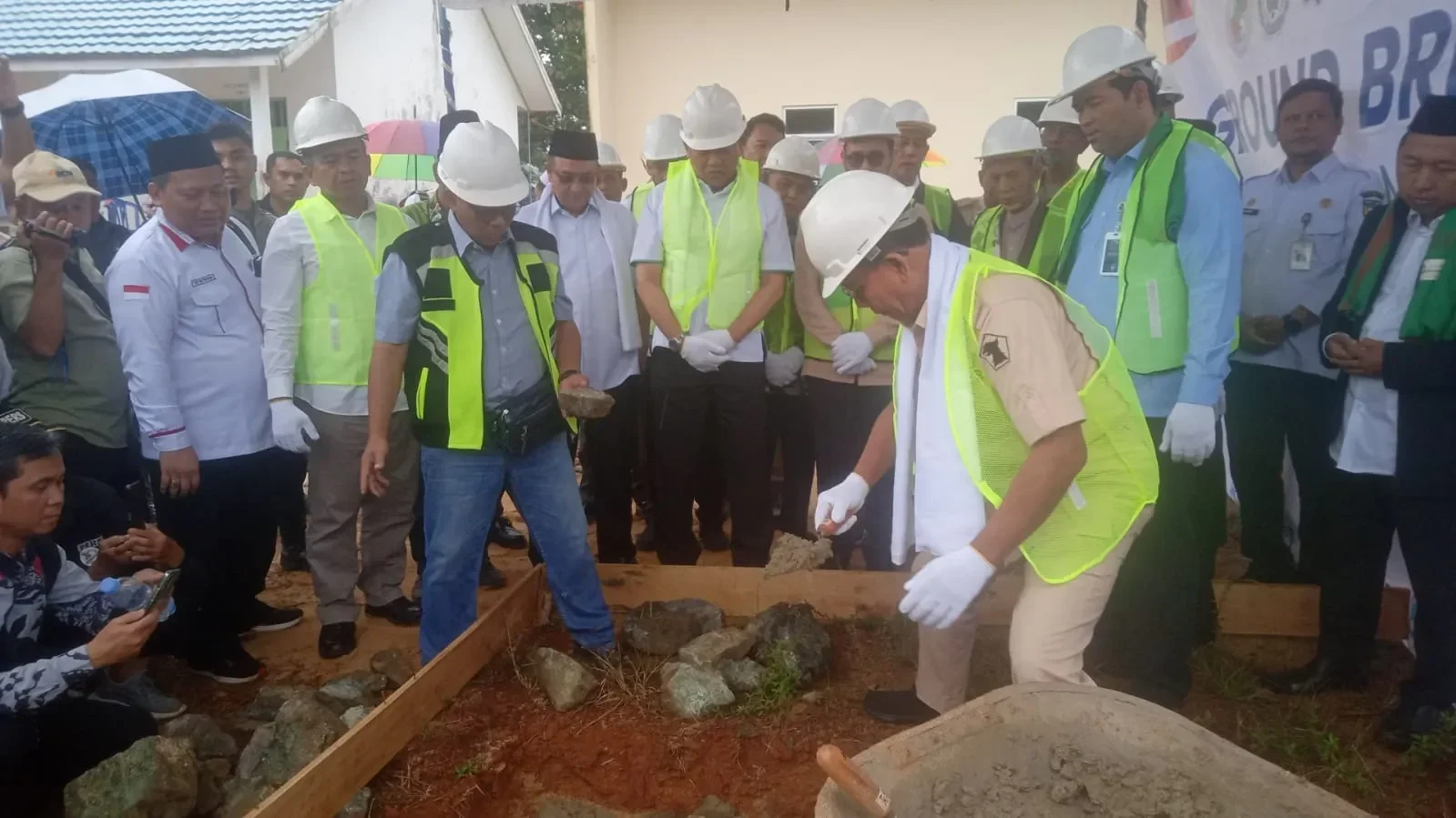 Peletakan batu pertama pembangunan dapur sekolah, sejumlah tokoh hadir mengenakan helm dan rompi.